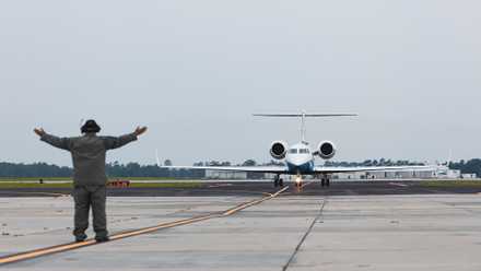 Cover, A Marine gives signals to an Air Force Gulfstream C-37A attached to the 99th Airlift Squadron.