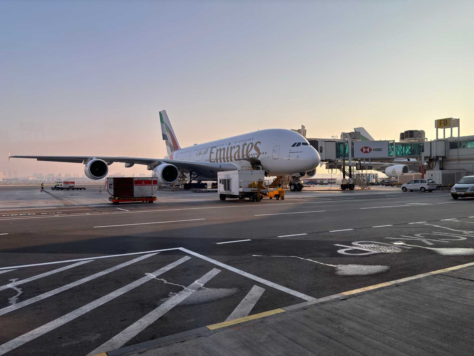 Emirates Airbus A380 on tarmac at Dubai International Airport in the evening.