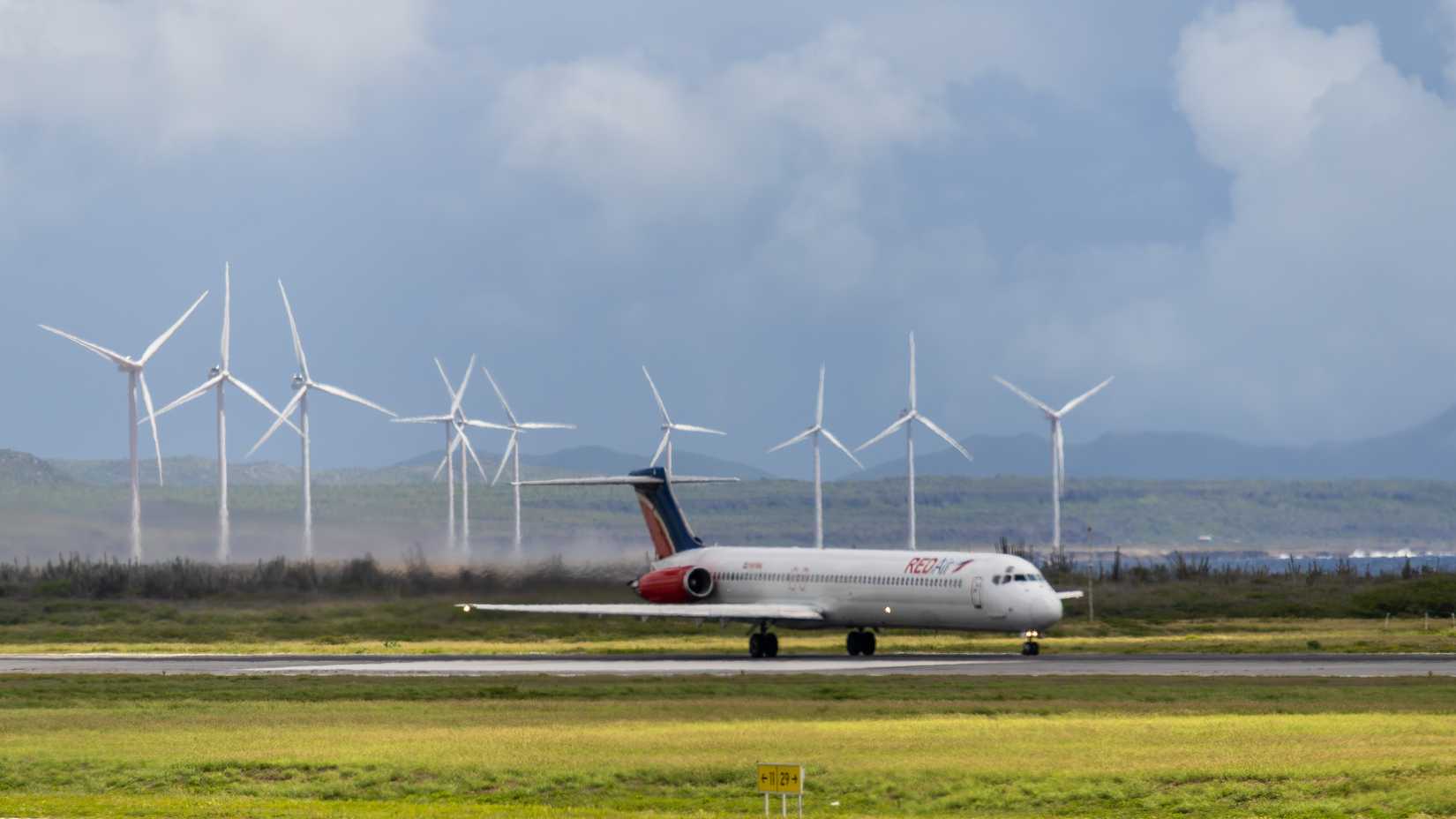 Red Air McDonell Douglas MD 80 rolling for takeoff on this iconic scene with the wind turbines in the background.