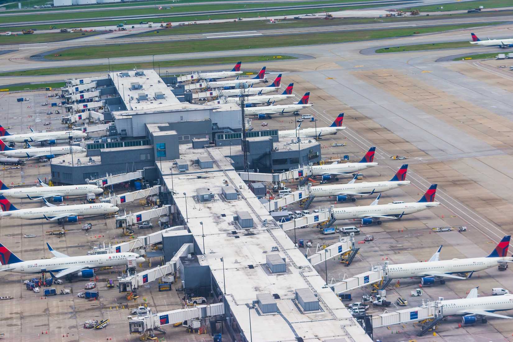 Aerial view of Concourse B building of Hartsfield-Jackson Atlanta International Airport and apron with many Delta airlines airplanes from ascending plane