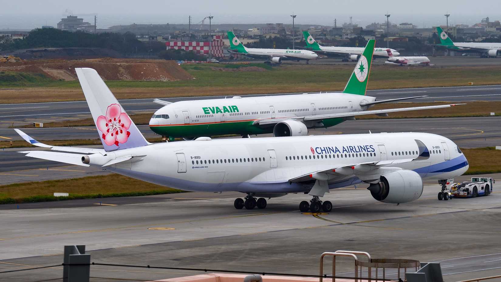 An Airbus a350-900 of China Airlines and a Boeing 777-300(ER) of EVA Air crosses paths on the taxiway at Taiwan Taoyuan International Airport