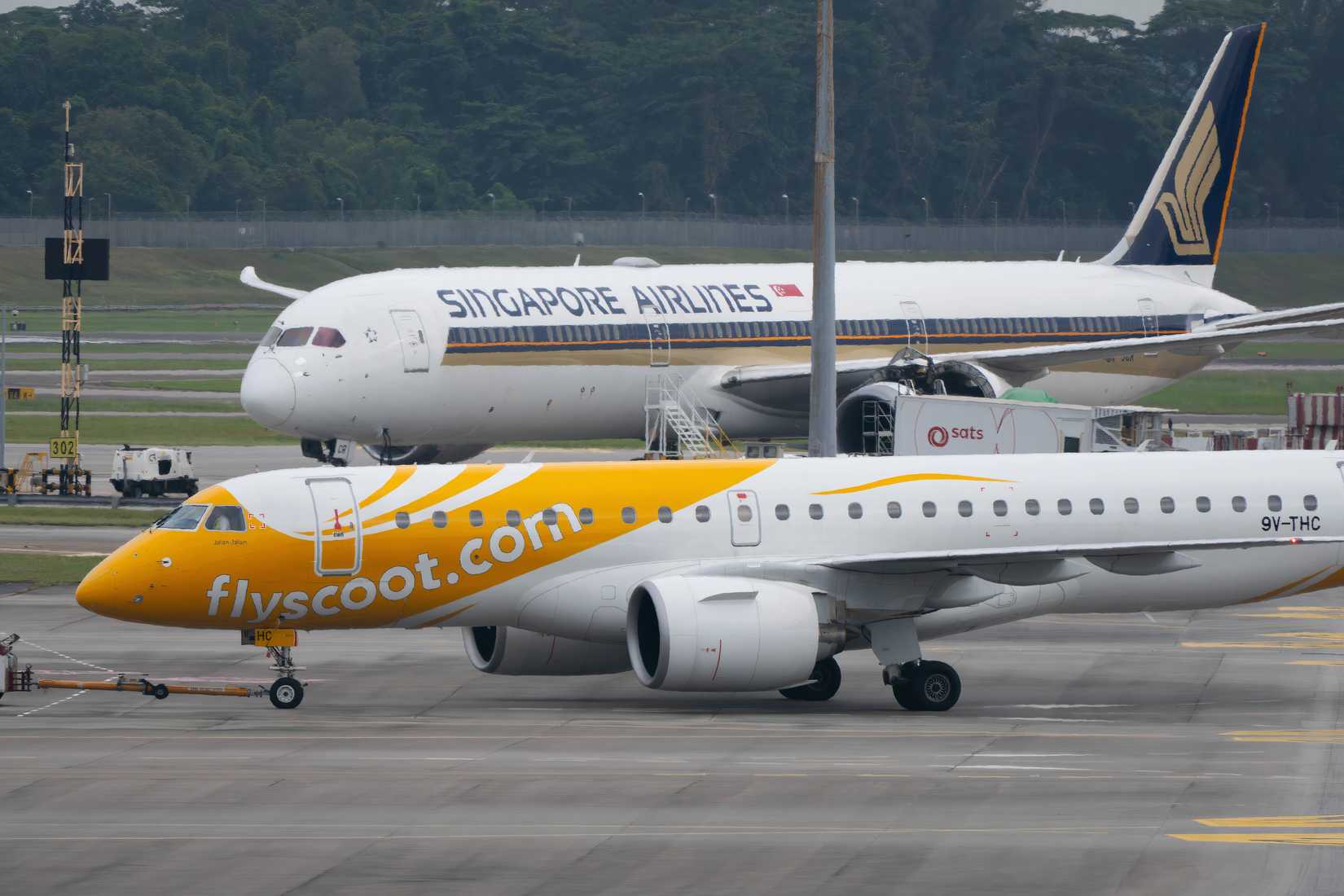 Scoot Embraer E190-E2 Pushing Back In Front Of A Singapore Airlines Boeing 787-10