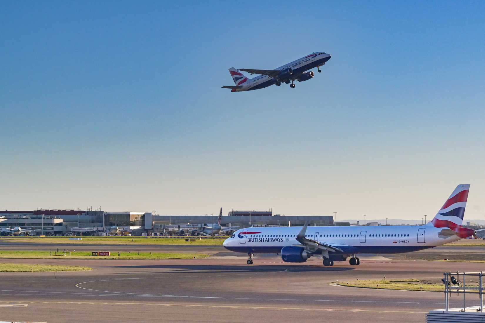 British Airways Airbus A321 Neo jet (registration G-NEOV) taxiing for take off at Heathrow airport. Another of the airline's jets is taking off in the background.