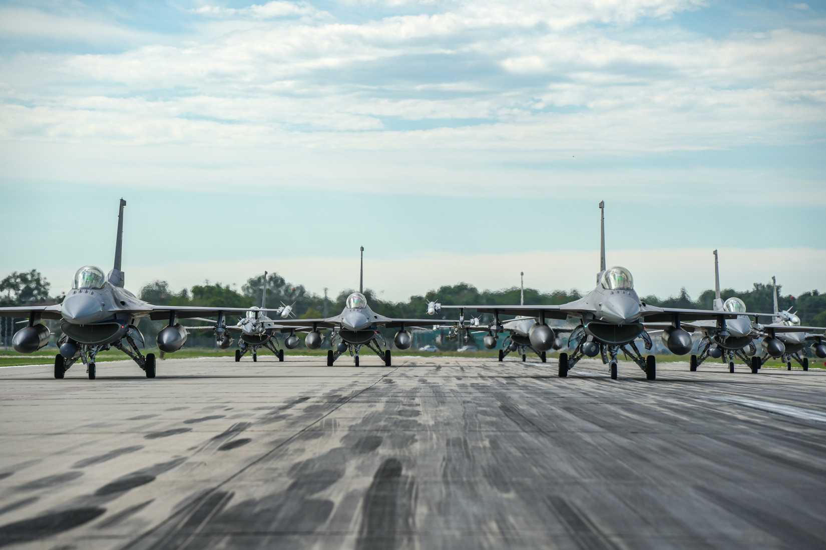 F-16 Fighting Falcons assigned to the 114th Fighter Wing line up in formation on the runway.