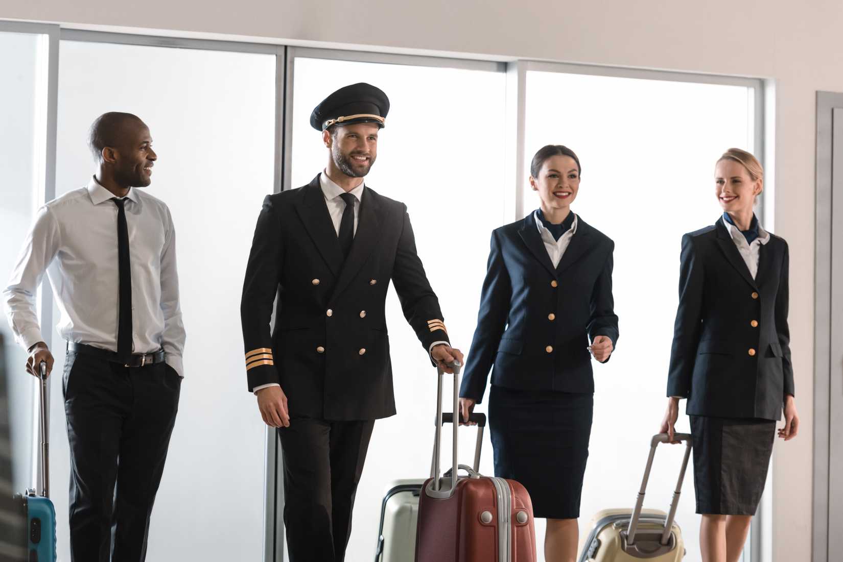 Four members of the flight crew in the airport with suitcases