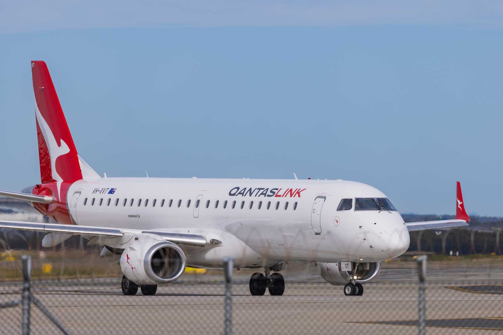 A QantasLink Embraer 190, Registration VH-XVT, operated by Alliance Airlines taxies out for departure.