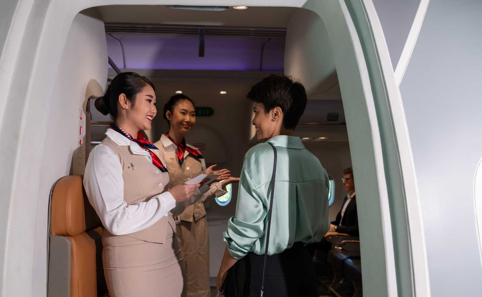 Two flight attendants and one passenger at aircraft door
