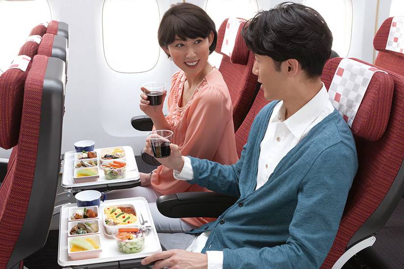 two passengers enjoying a meal in japan airlines economy class