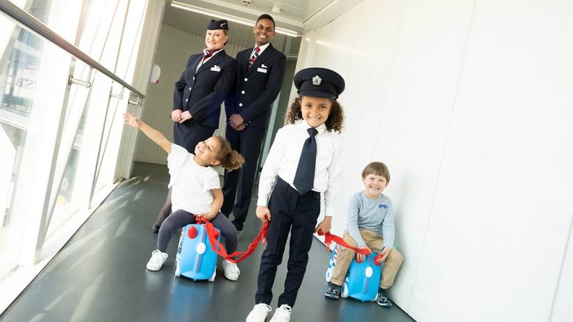 children playing on suitcases at airport with cabin crew