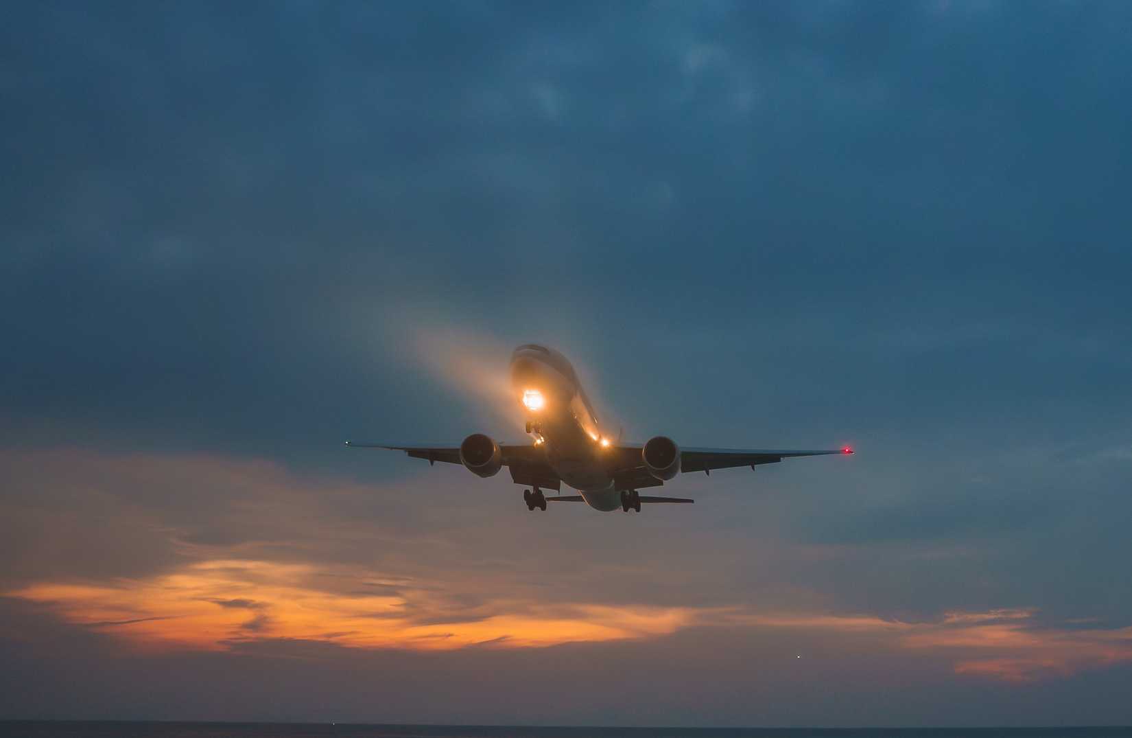 At dusk, civilian planes fly low over Mai Kaew Beach, their landing lights on.