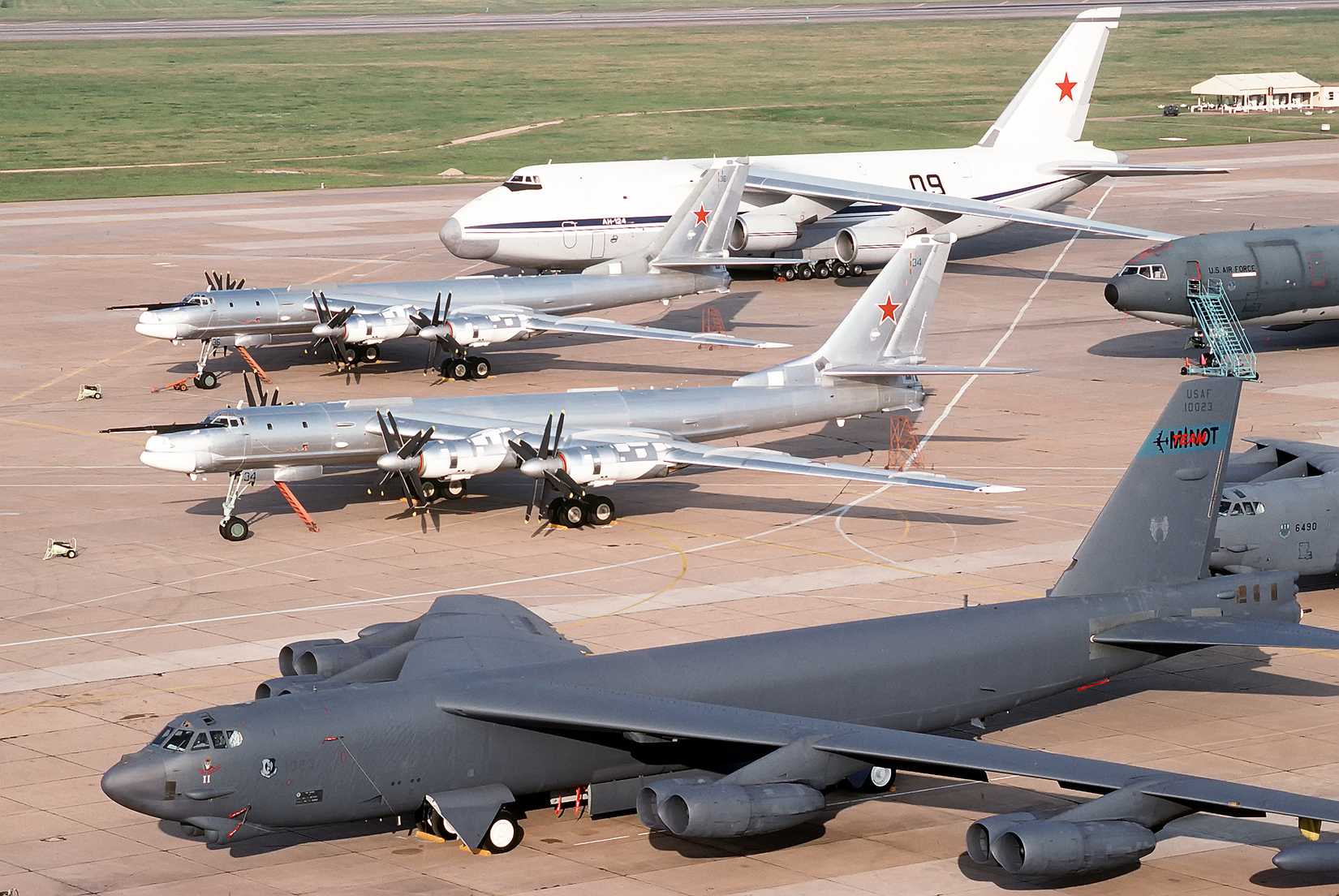 Two Tu-95 Bear-H bomber aircraft, center, and an AN-124 Condor transport aircraft of the Russian military, background, are parked on the flight line beside a B-52H Stratofortress aircraft of the 62nd Bombardment Squadron.