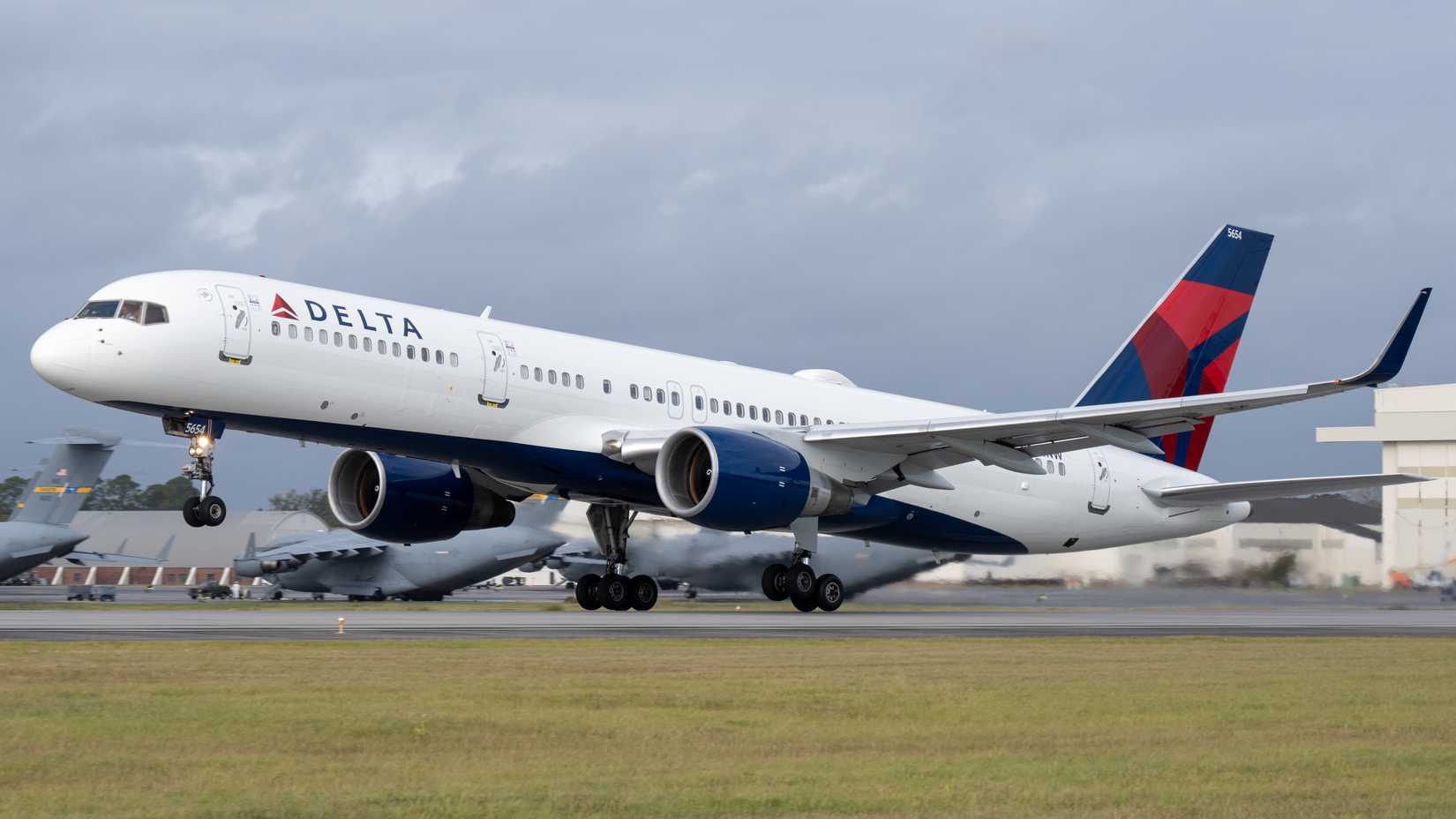 Delta Air Lines Boeing 757 airplane taking off from a runway with cloudy sky.