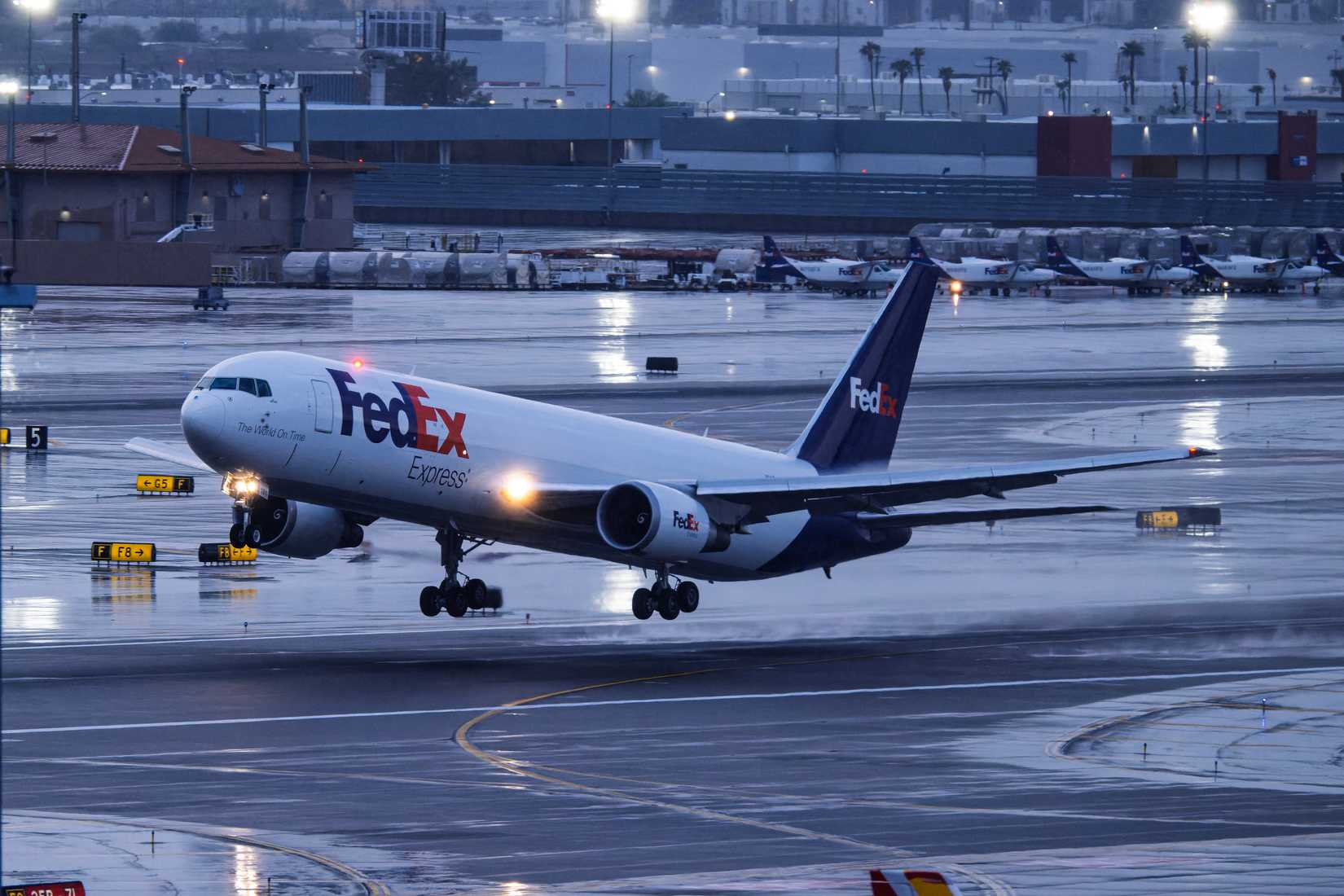 Partida do Boeing 767-300F N181FE da edEx Express da pista 7L em um aeroporto Phoenix Sky Harbor Intl sob forte chuva.