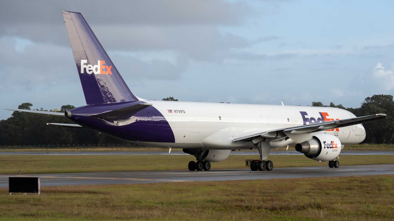 Avião de carga Boeing 757 da FedEx taxiando em uma pista com céu nublado.