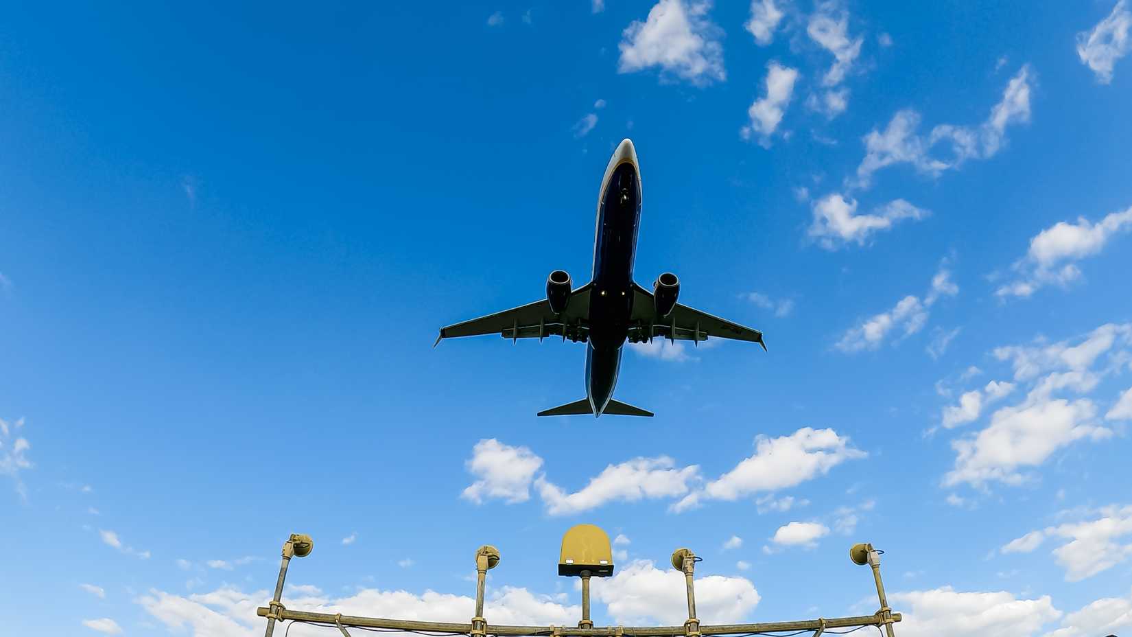 Majestic aircraft soaring through a clear blue sky over an airport runway in the afternoon light