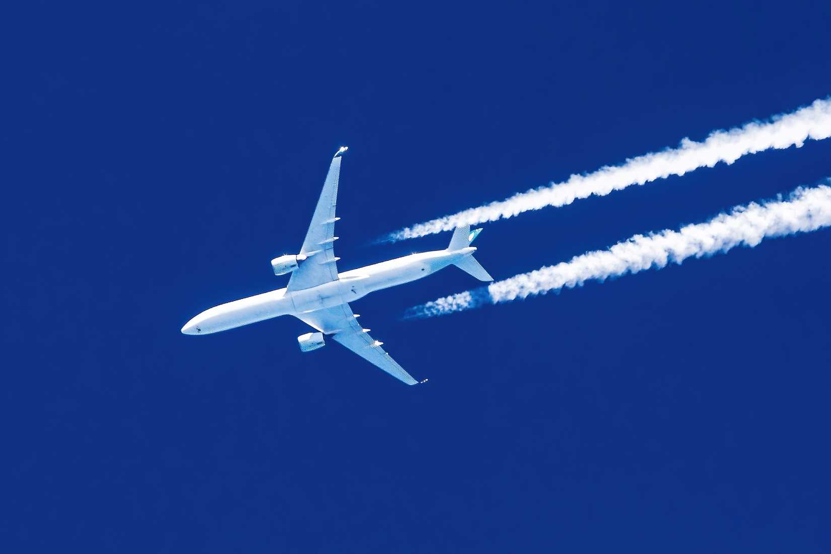 Sharp telephoto close-up of jet plane aircraft with contrails cruising from Hong Kong to New York,