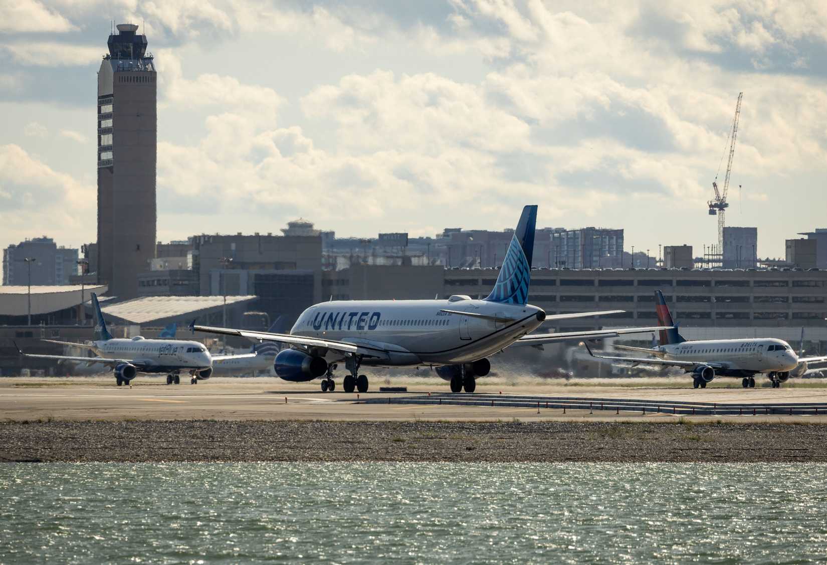 United Airlines plane preparing for takeoff at Boston's Logan Airport with other planes taxiing.