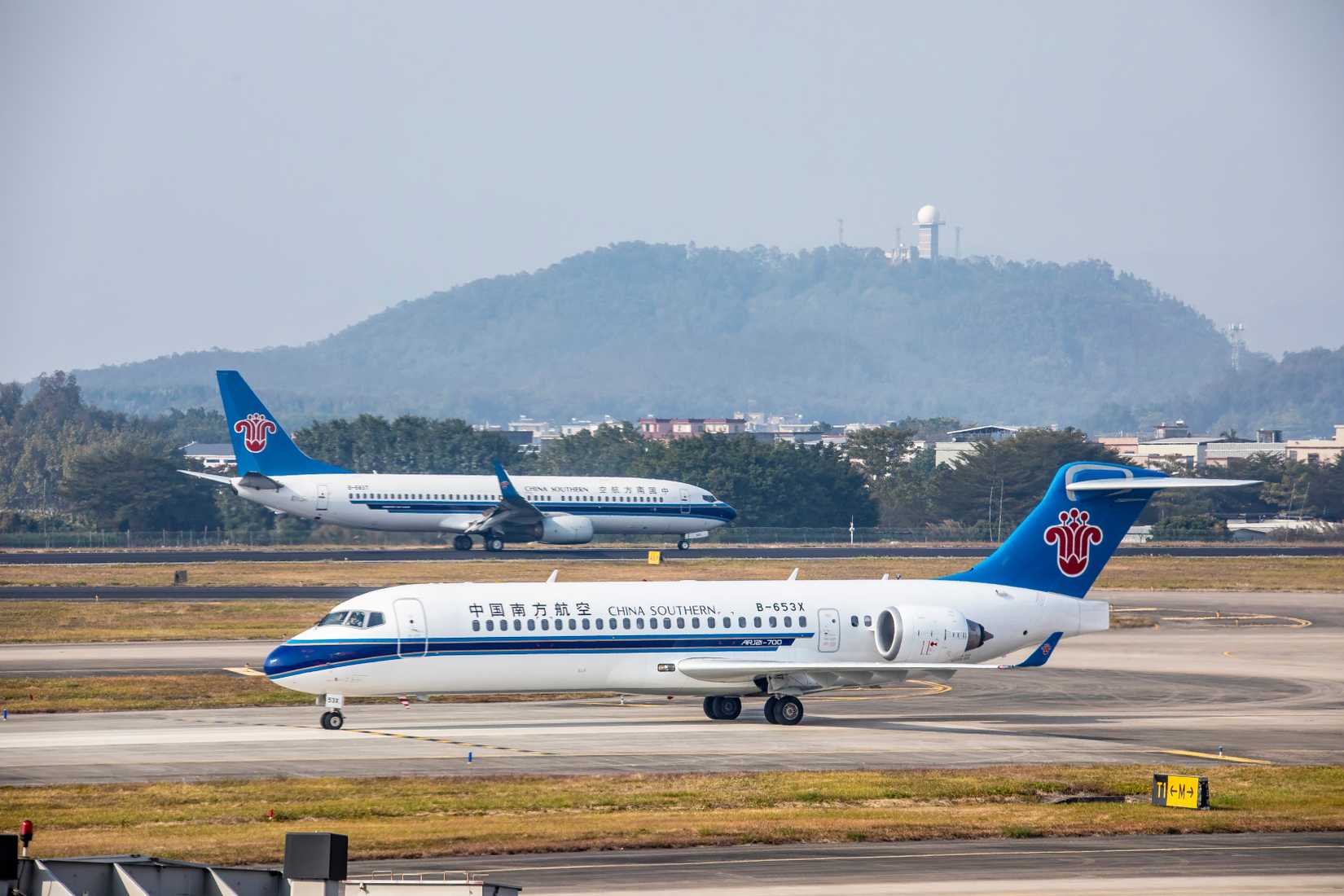 wo China Southern Airlines aircraft are taxiing on the runway at Jieyang Chaoshan Airport, one of which is a COMAC C909 regional aircraft.