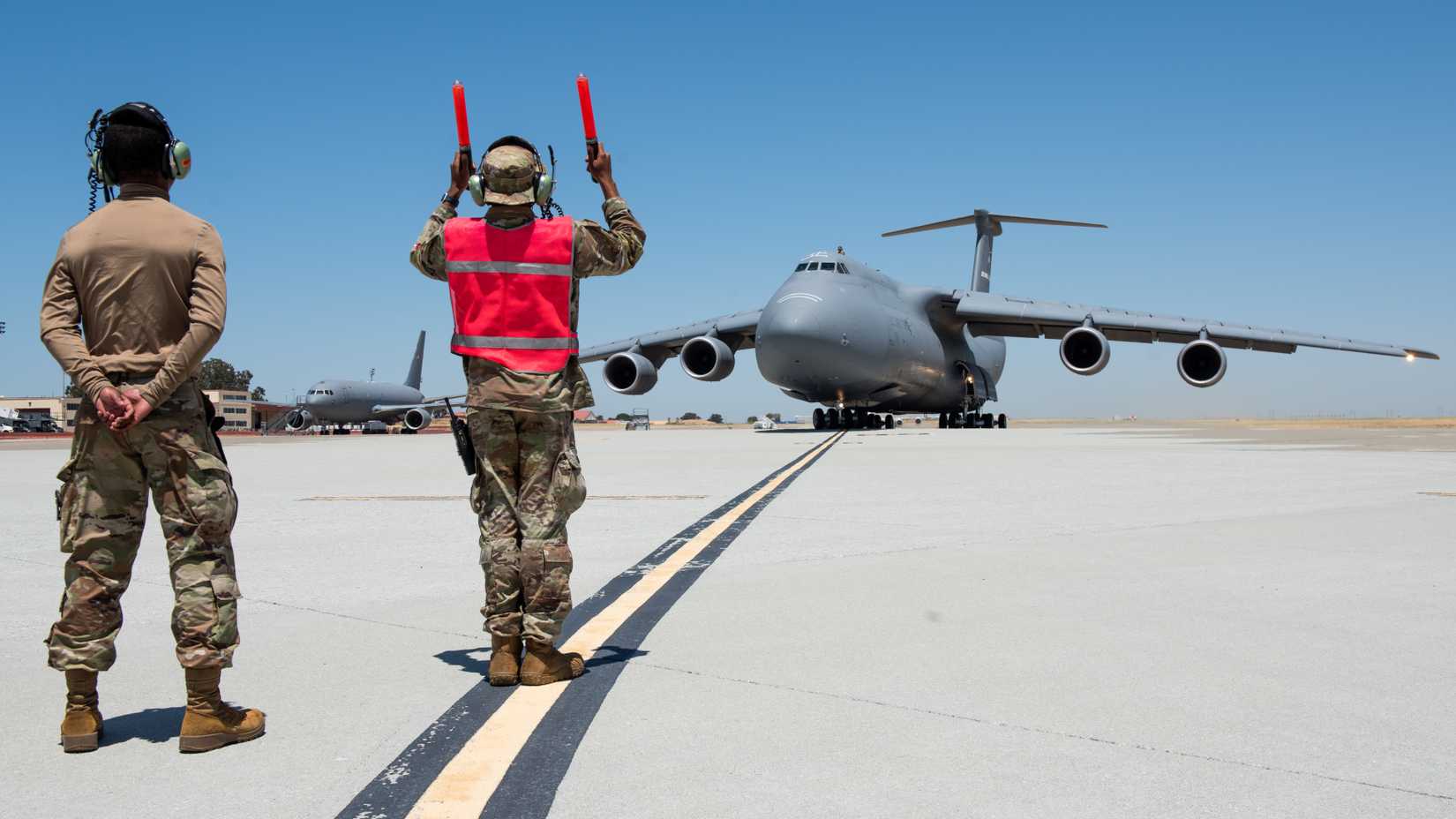 Airmen direct a C-5M Super Galaxy assigned to the 22nd Airlift Squadron on the flight line at Travis Air Force Base
