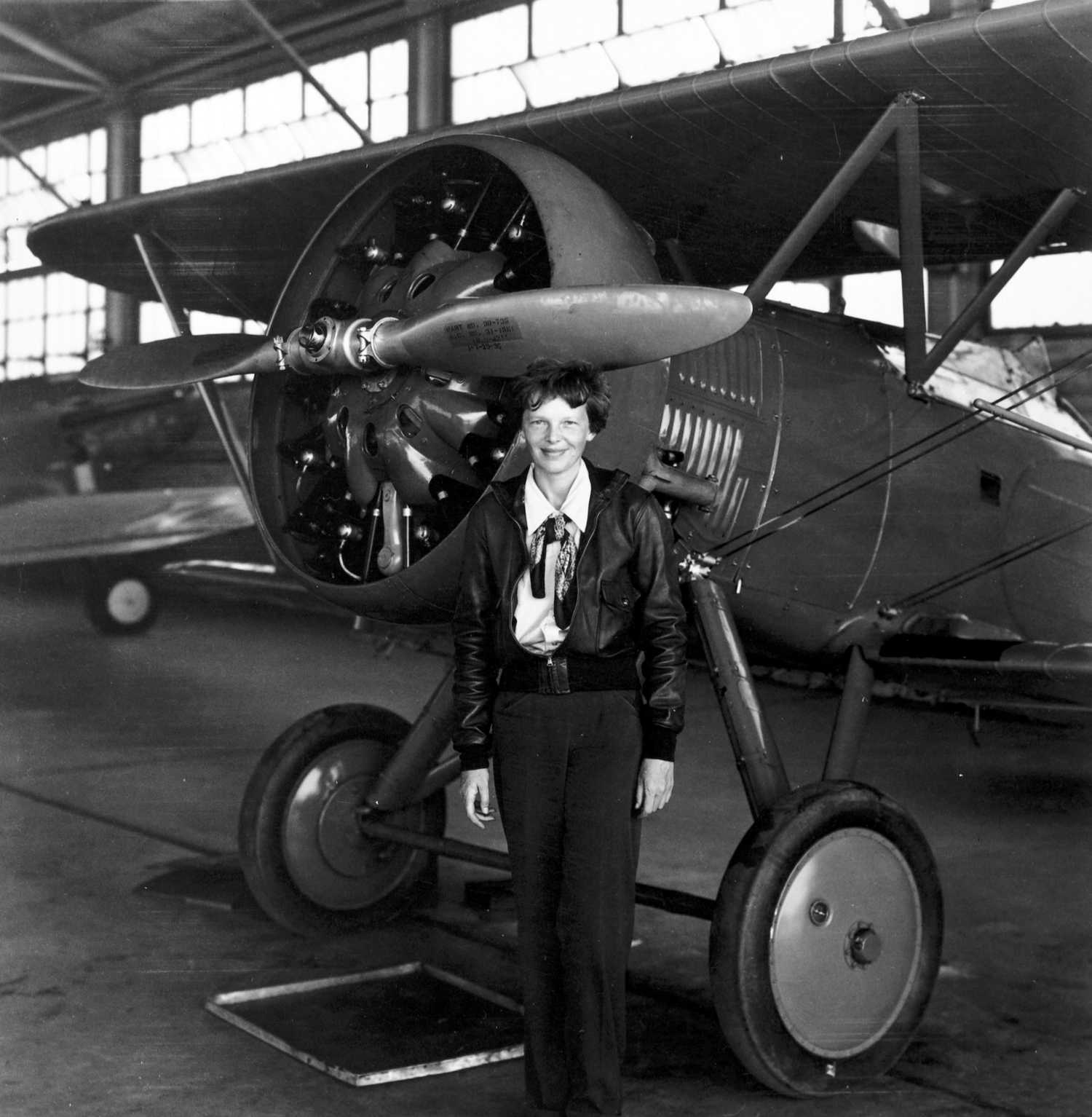 Amelia Earhart in a hangar with one of her planes