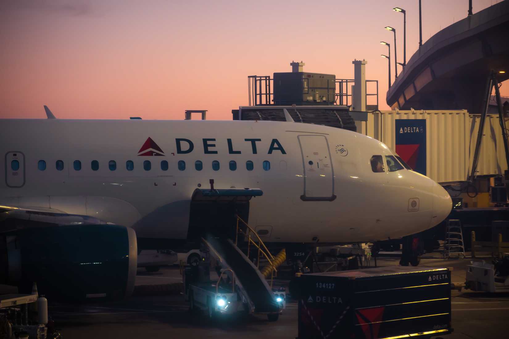 Delta airlines flight at DFW international airport gate in Dallas during sunset.