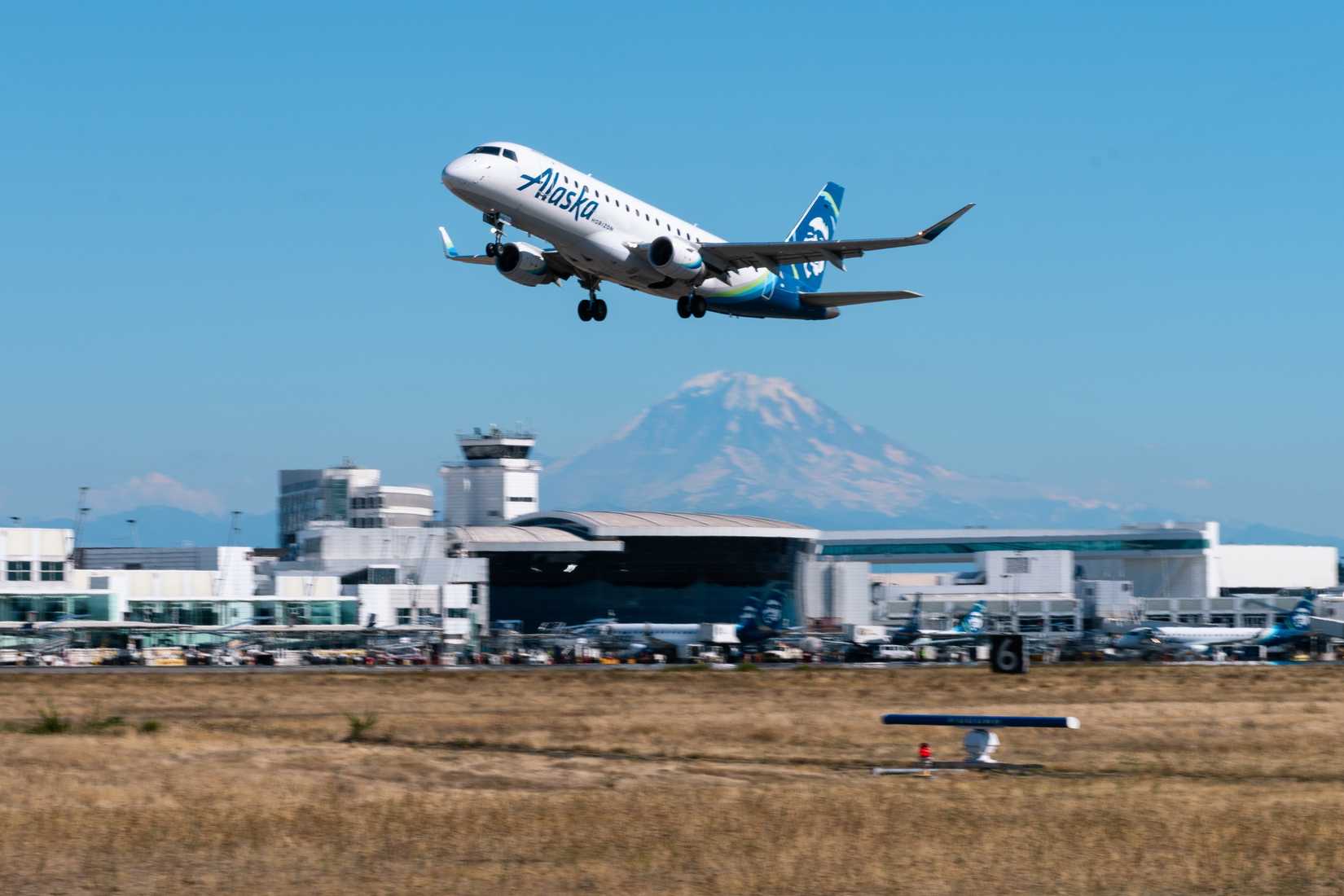 Horizon Air Embraer E175 Rising From Seattle-Tacoma International Airport With Mount Rainier and Horizon Air Terminal in Background
