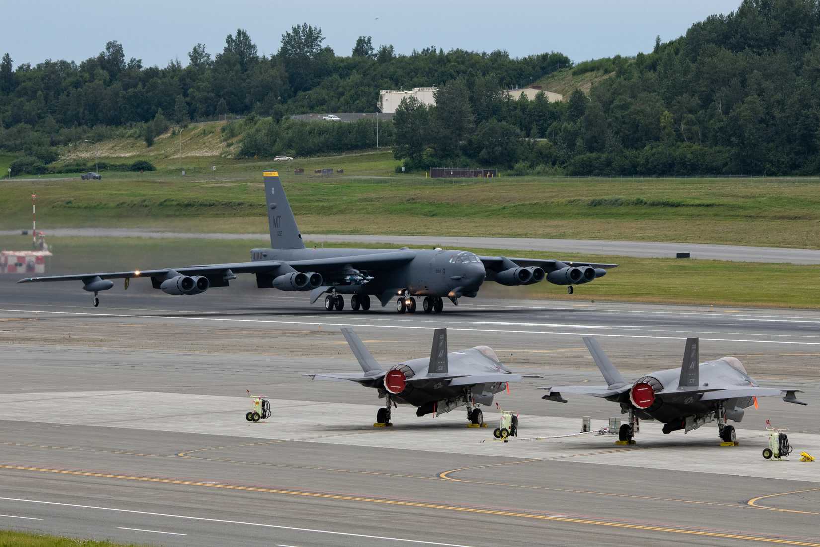 Air Force B-52 Stratofortress assigned to the 5th Bomb Wing takes off in front of 354th Fighter Wing F-35 Lightning IIs