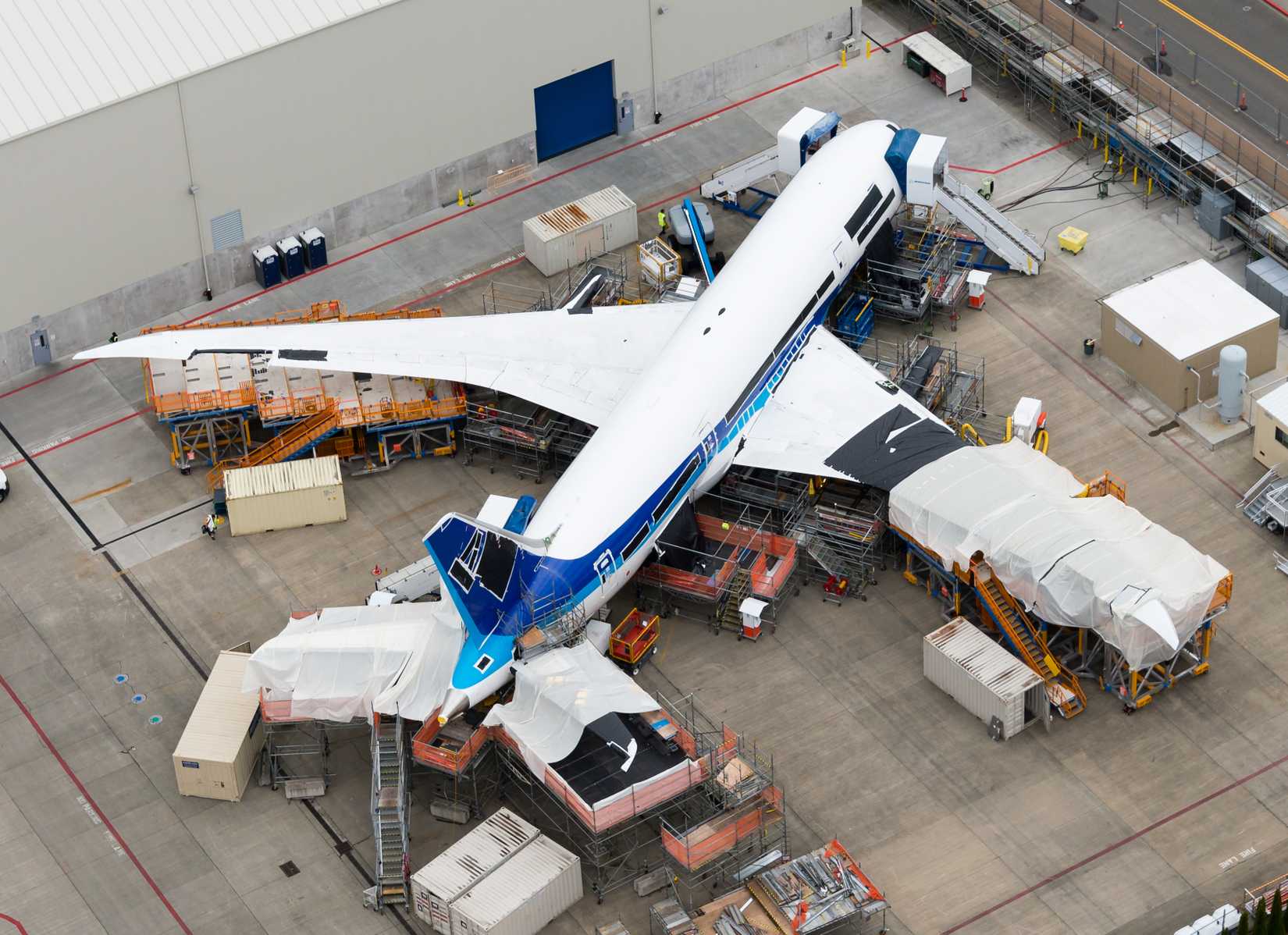 One of the first Boeing 787 Dreamliner ever produced going through heavy rework in weight and structural bodies. Scaffolding, stairs and lone visible.-1