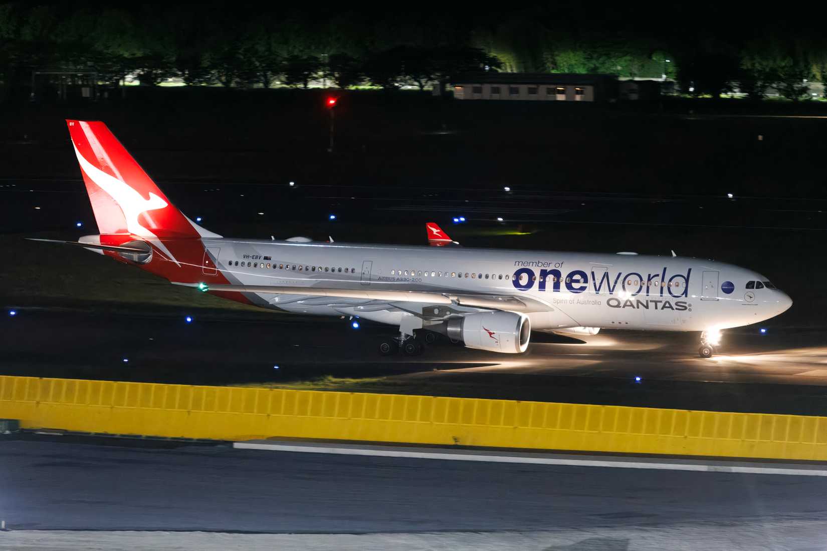 Qantas Airbus A330-200 wearing One World alliance livery taxiing to runway 16R for a night departure to Australia