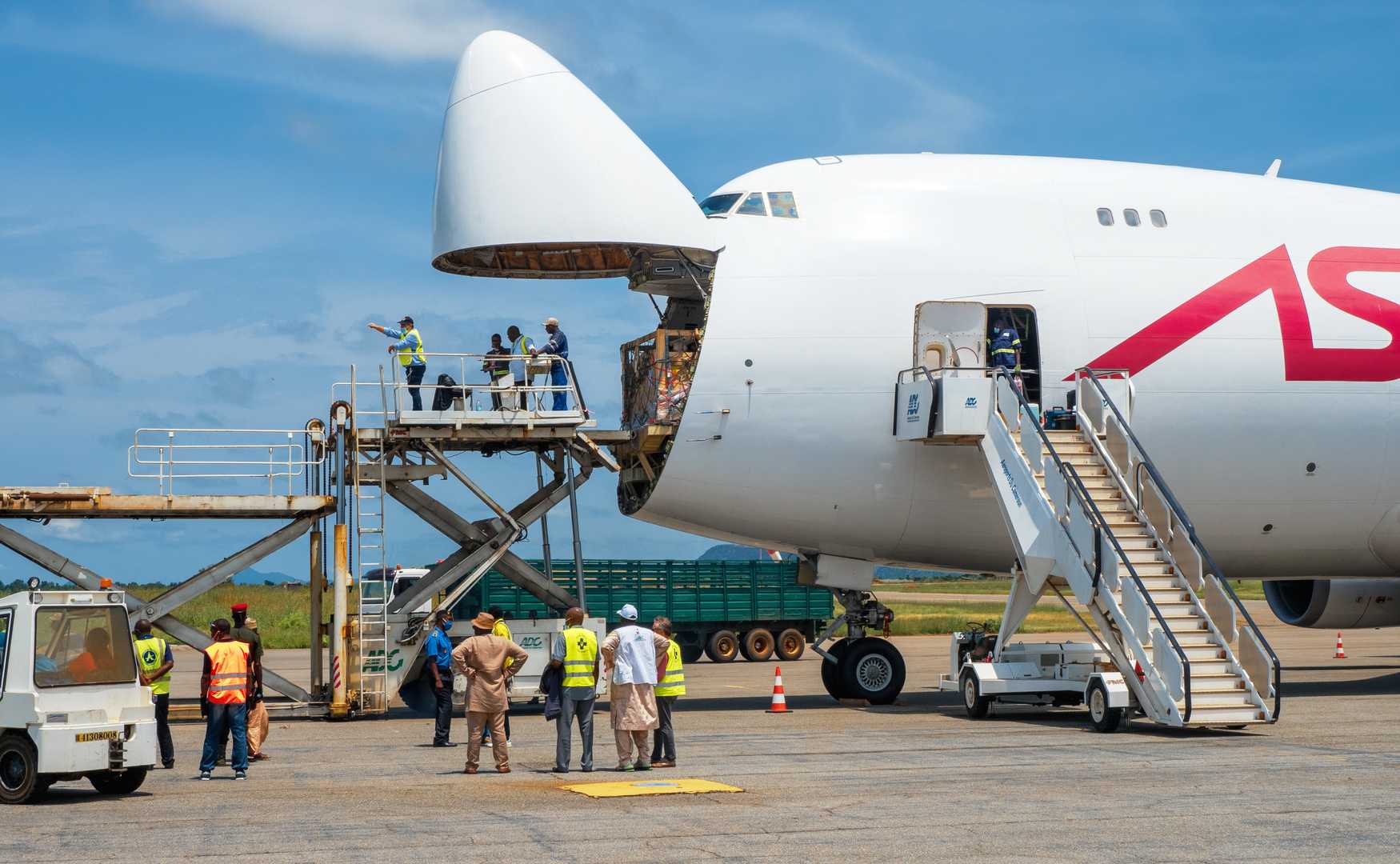 A Boeing 747 Jumbo Jet freighter aircraft with a wide open nose cargo door being offloaded.