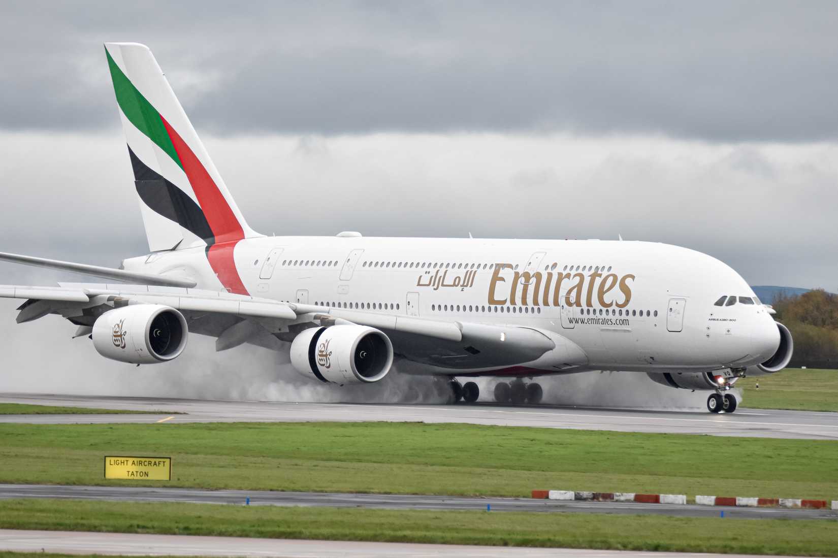 Emirates Airbus A380 A6-EVQ arriving at a rainy Manchester Airport.