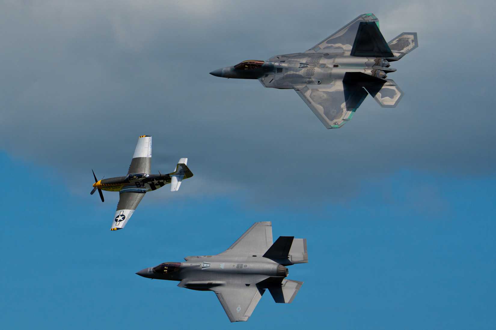F-22 Raptor in formation with a P-51 Mustang and an F-35A Lightning II.