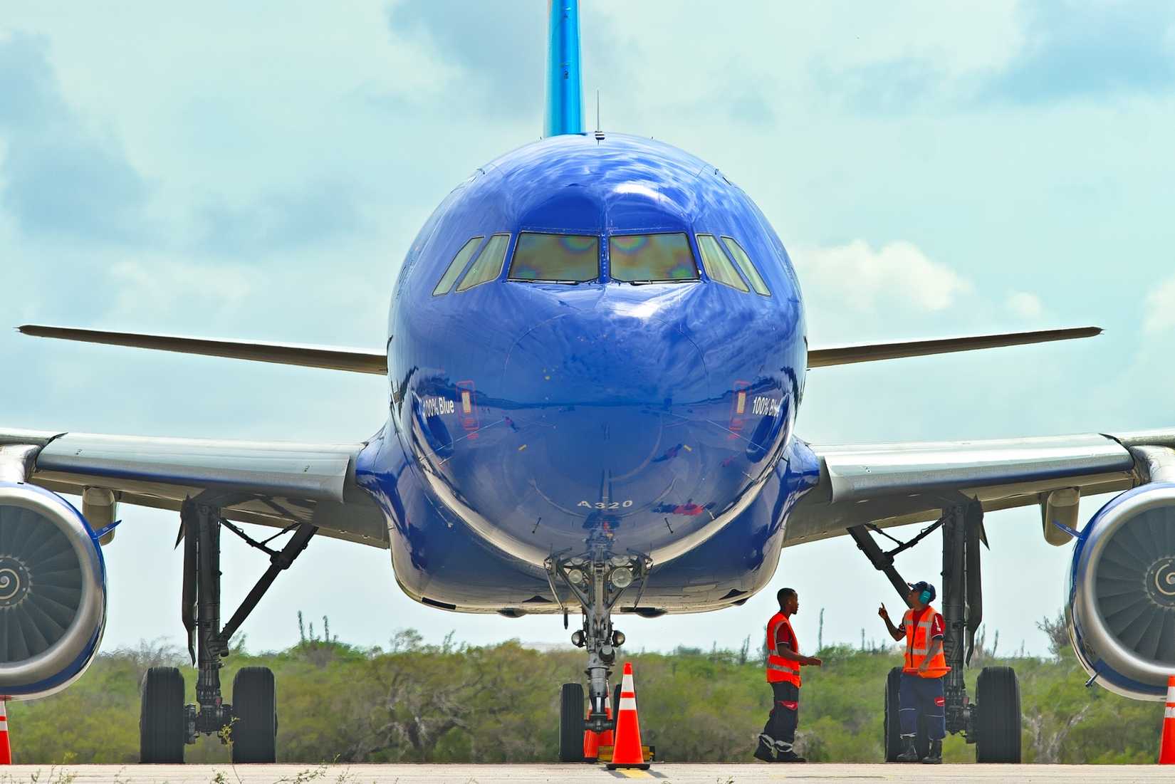 JetBlue Airbus A320 Commercial Aircraft on a parking spot with Ground Crew at Tropical Airport.
