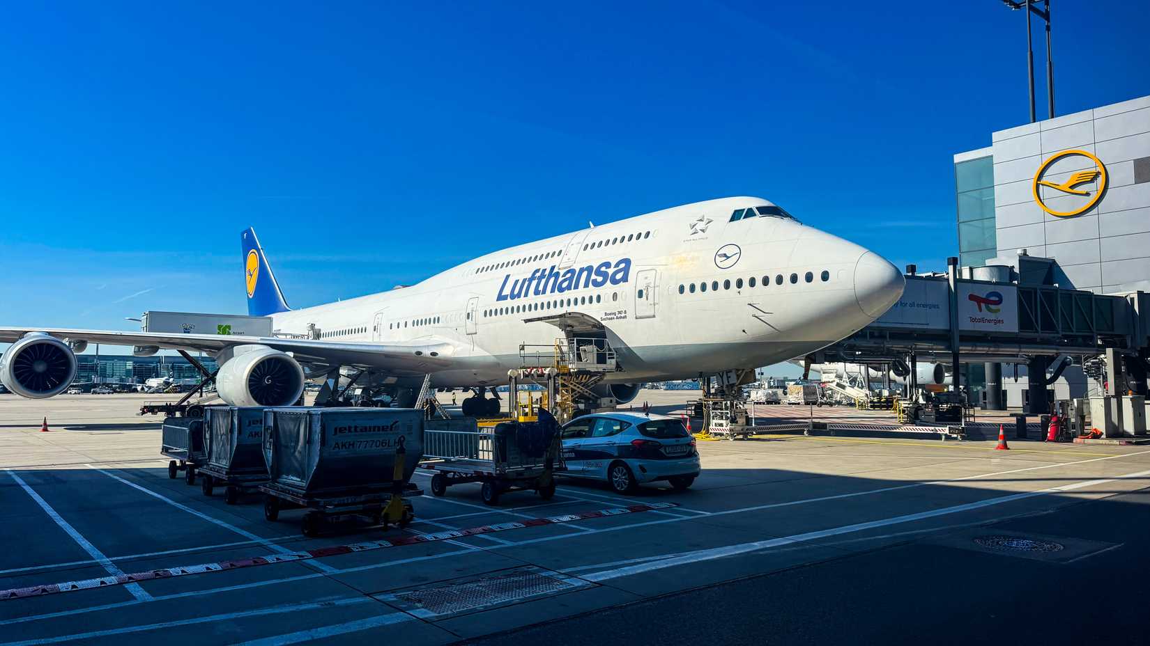 Lufthansa Boeing 747 jumbo jet aircraft parked at the airport terminal gate.
