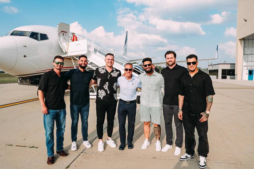Players pose in front of the air stairs to the Detroit Tigers 737.