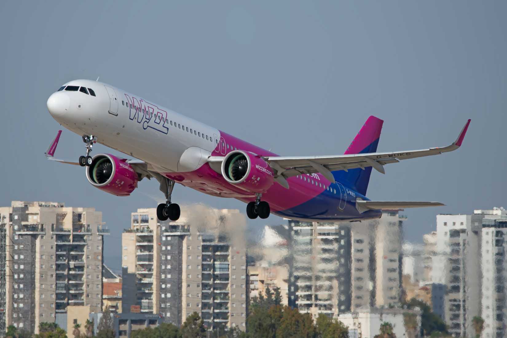 Ben Gurion Airport, Israel – Wizz Air Airbus A321neo G-WUKS taking off over Gush Dan buildings