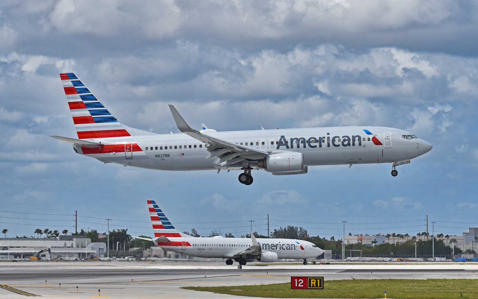 Two American Airlines (AA) Boeing 737-800 airplanes, N880NN and N827NN, departing and arriving at Miami International Airport (MIA) on a stormy day.