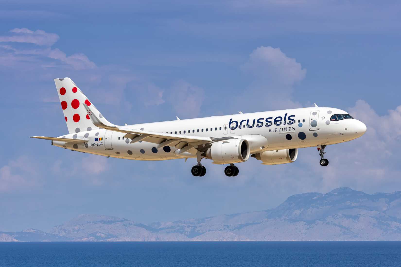 Brussels Airlines A320neo coming to land flying over the sea, with mountains in the background