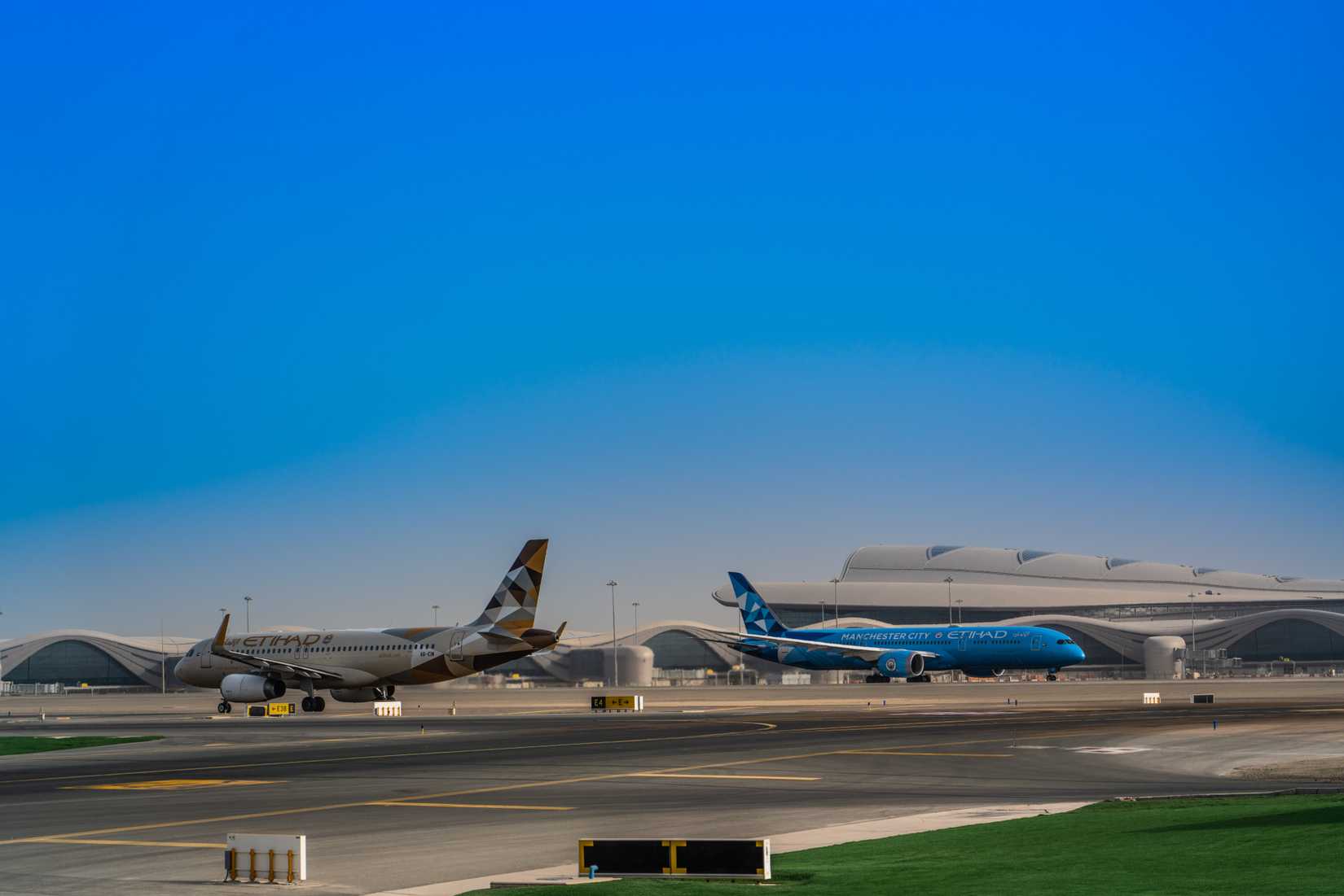 Etihad Manchester City livery 787 and A320 aircraft taxiing at Abu Dhabi airport