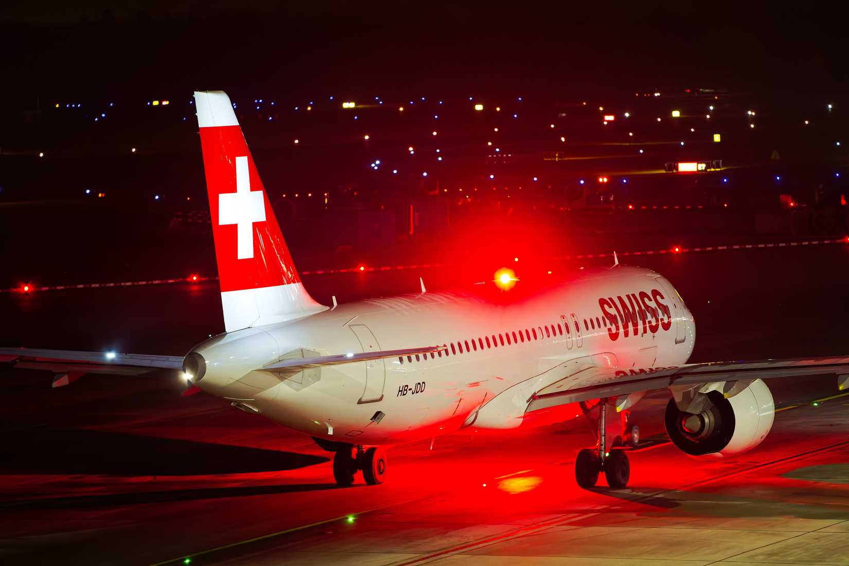 High angle view of Swiss passenger airplane Airbus A320-271N registration HB-JDD type taxiing on a dark winter night.