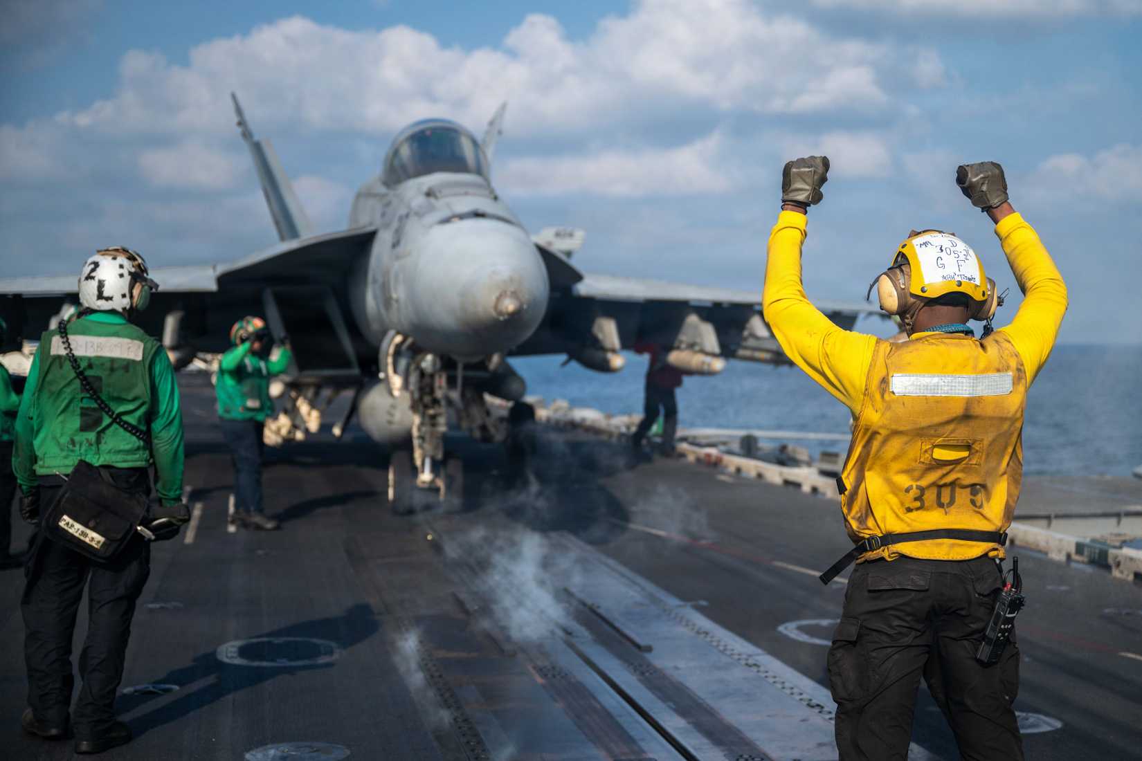 Sailor signals an FA-18E Super Hornet, attached to Strike Fighter Squadron (VFA) 14, on the flight deck of Nimitz-class aircraft carrier USS Abraham Lincoln (CVN 72).