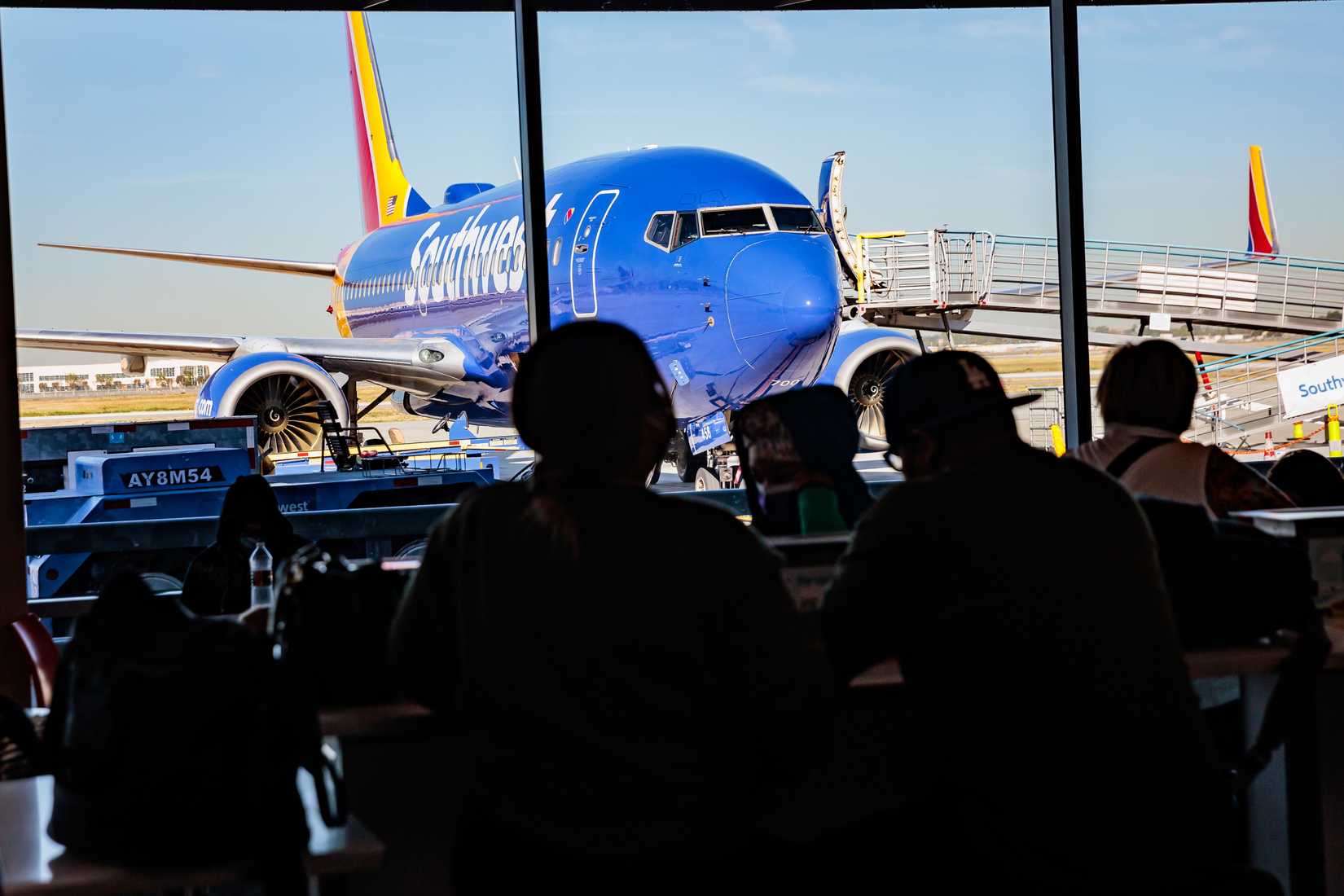 Passengers wait for their flights near the Southwest Airlines gate inside of the Long Beach Airport concourse.