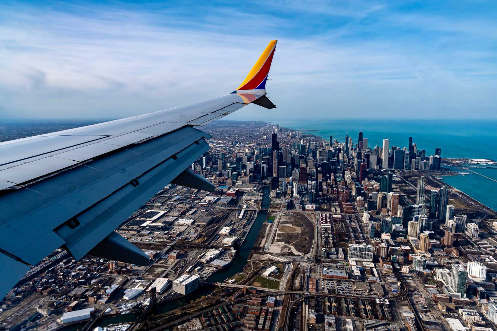 View of the downtown area of Chicago, IL during the early evening as seen from an airplane. The aerial view also shows the wing of the plane.