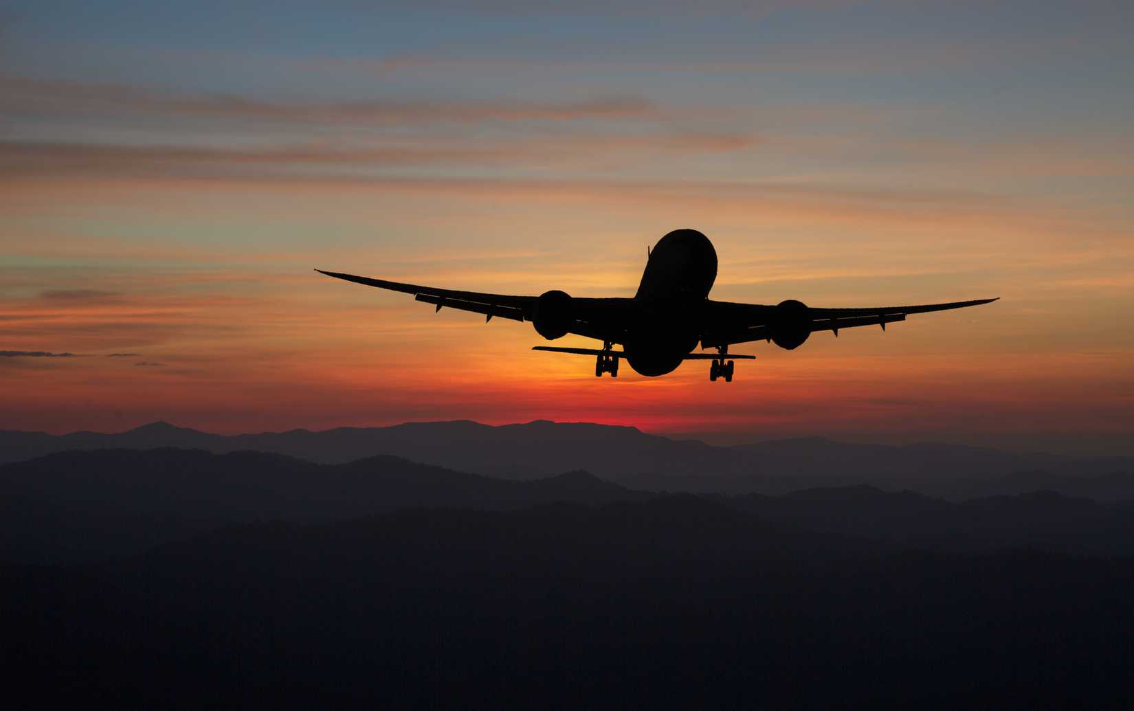 Silhouette of a 787 flying away into the sunset