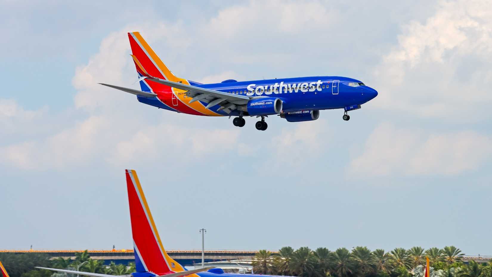 Southwest 737-700 coming in to land while another southwest aircraft waits beside