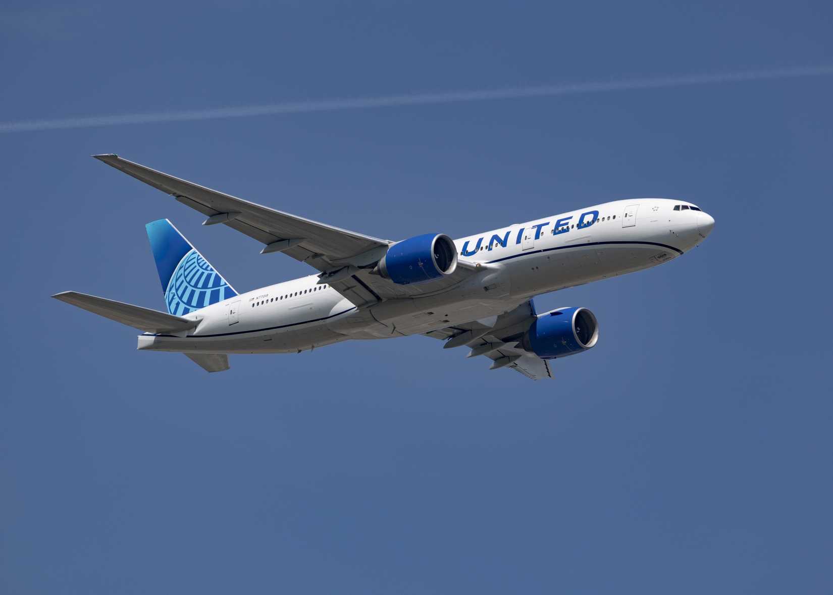 United Airlines, Boeing 777, Reg N77019 taking off into a clear blue sky.