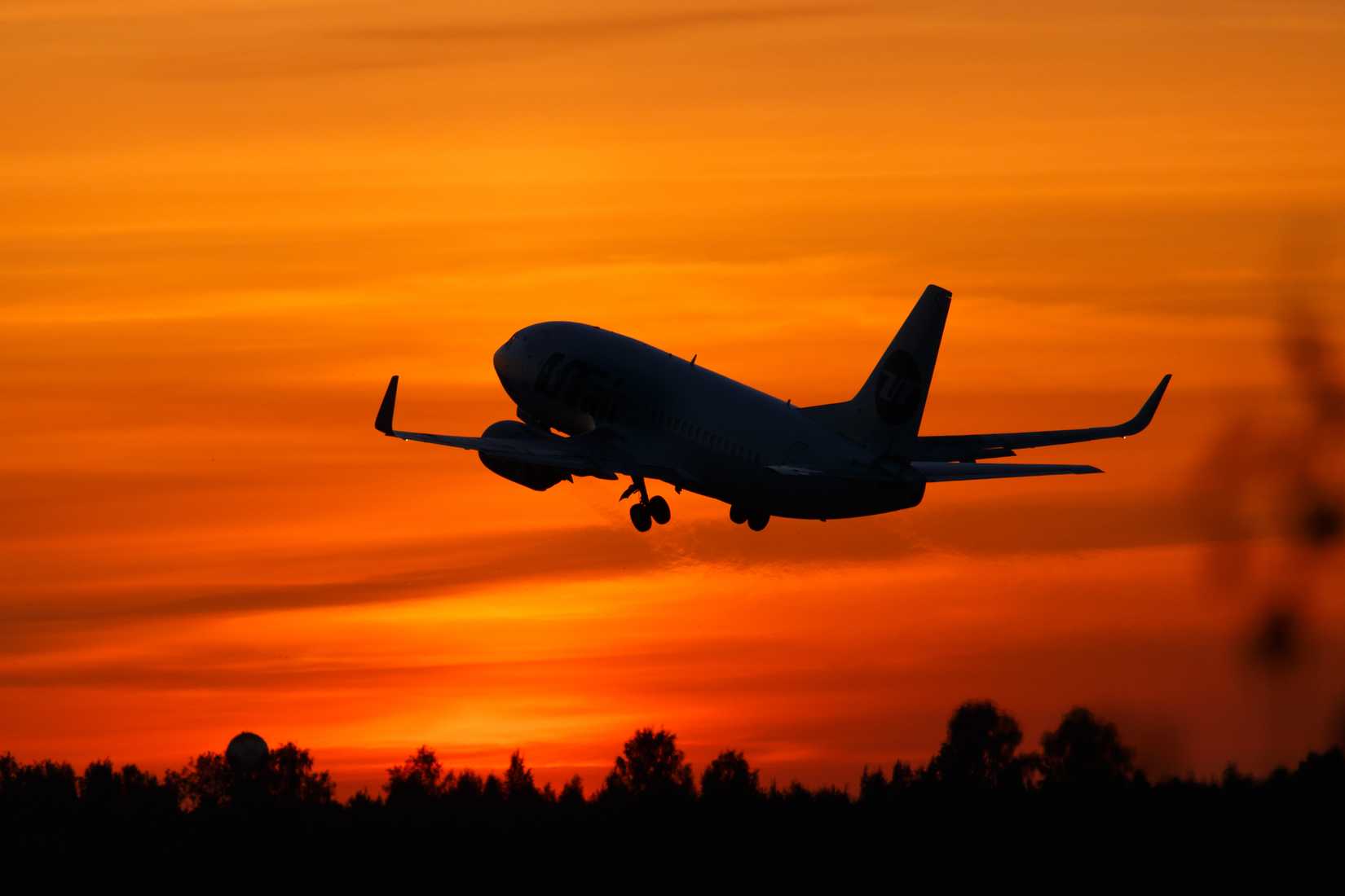 Boeing 737 silhoutte flying with sun setting behind it