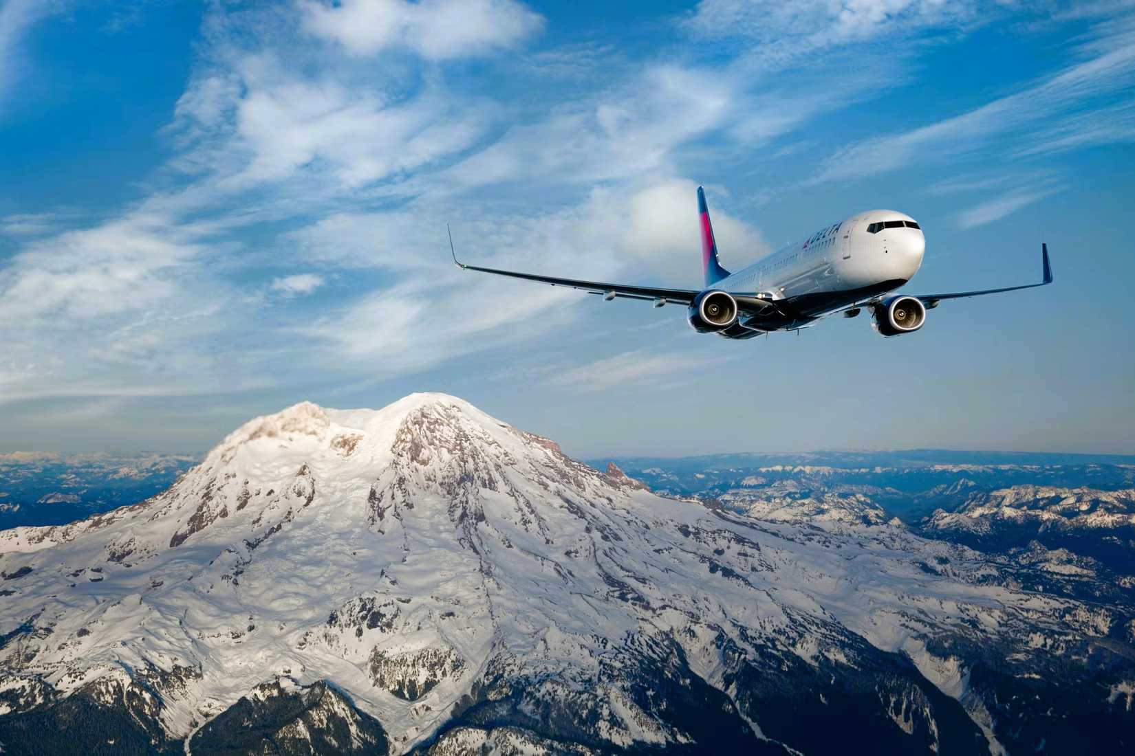 Delta Air Lines Boeing 737-900 flies over snow capped mountains