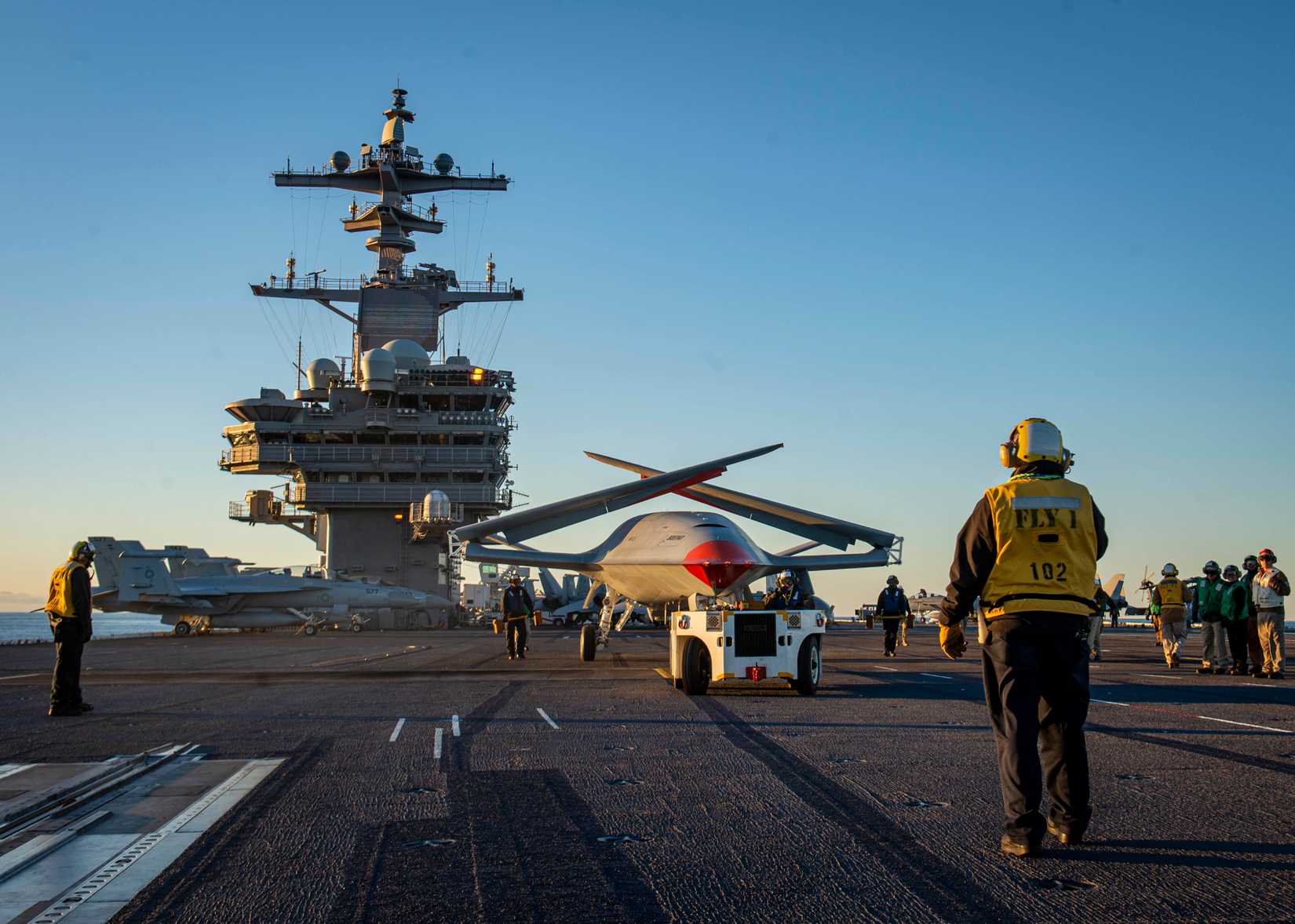 A Boeing unmanned MQ-25 aircraft is given operating directions on the flight deck aboard the aircraft carrier USS George H.W. Bush (CVN 77).