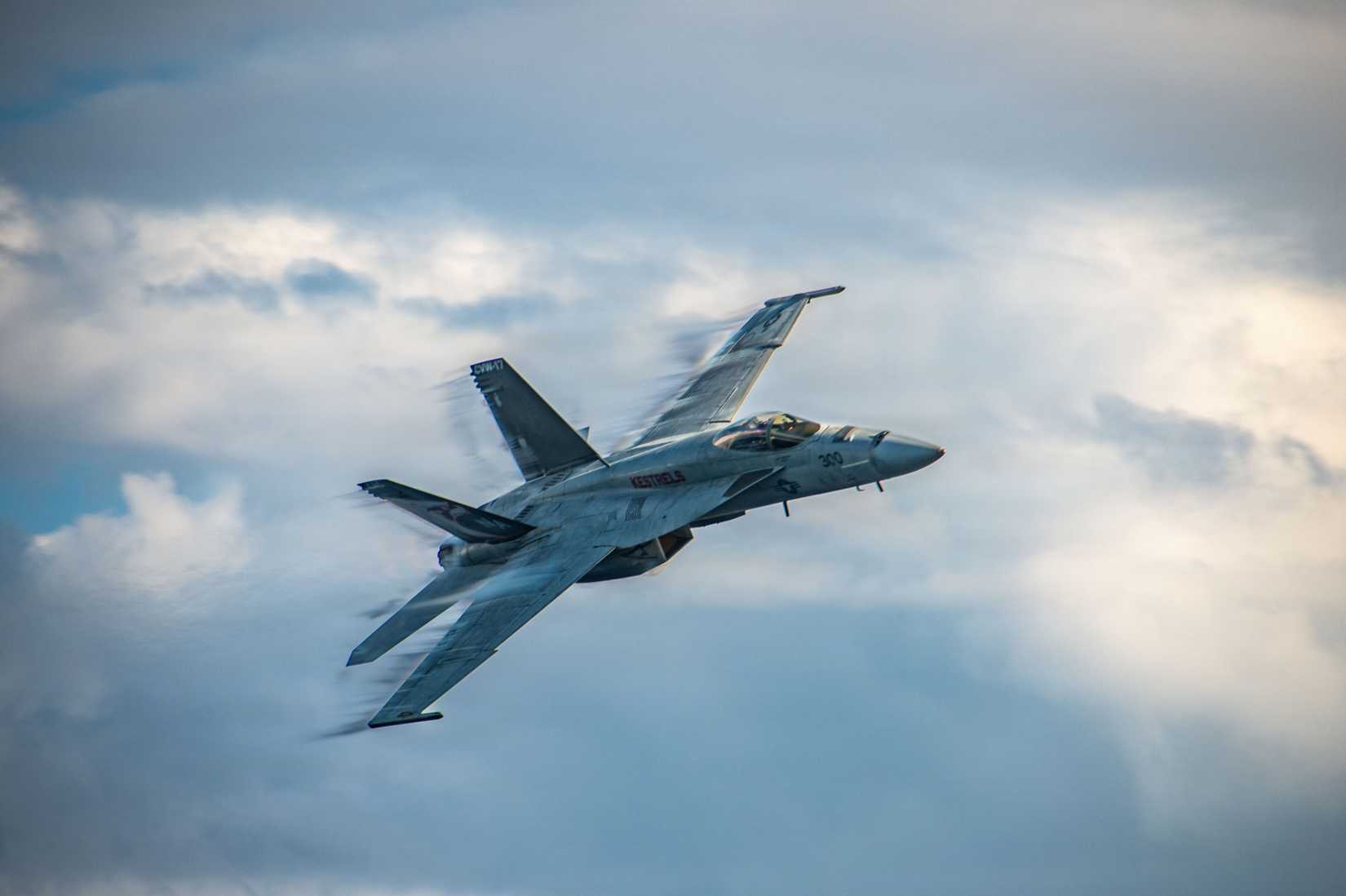 A FA-18E Super Hornet performs a high-speed flyby of USS Nimitz during a ceremony.
